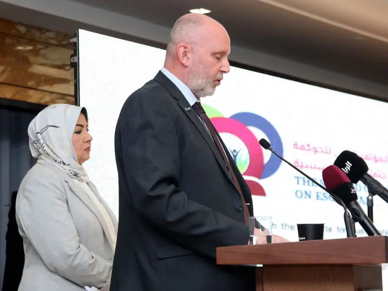 A speaker addressing the hall from the lectern, 2025.