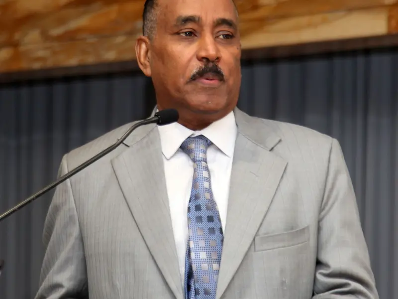 A speaker addressing the hall from the lectern, 2025.