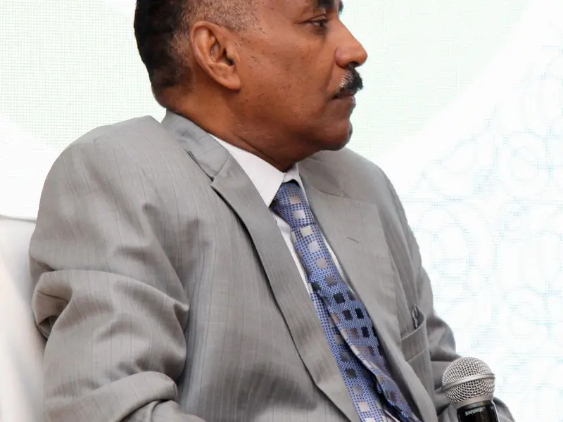 A speaker addressing the hall from the lectern, 2025.