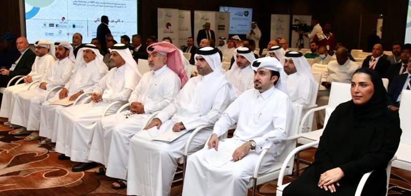 Front-row dignitaries, including a woman in a black abaya, seated at the opening of the Second Conference on ESG Qatar 2025, with sponsor banners and a cameraman behind them.