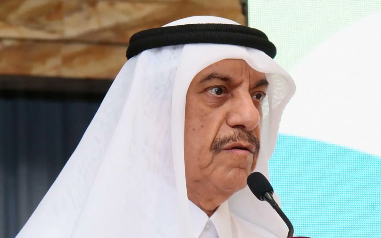 A senior Qatari official speaking into the podium microphone during ESG Qatar 2025.